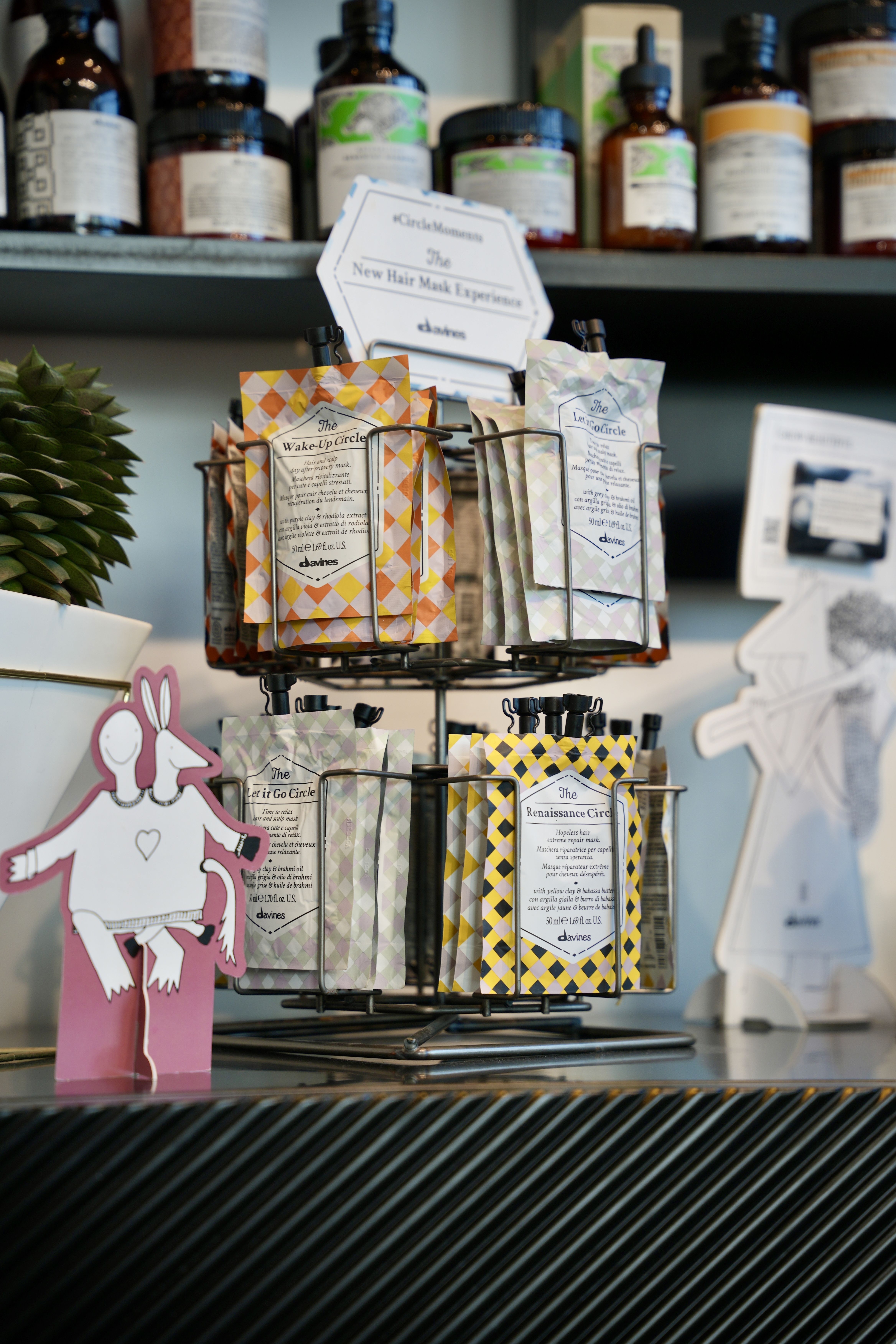 A Davines product display rack at Mod Salon, with sample sachets and the Davines mask card