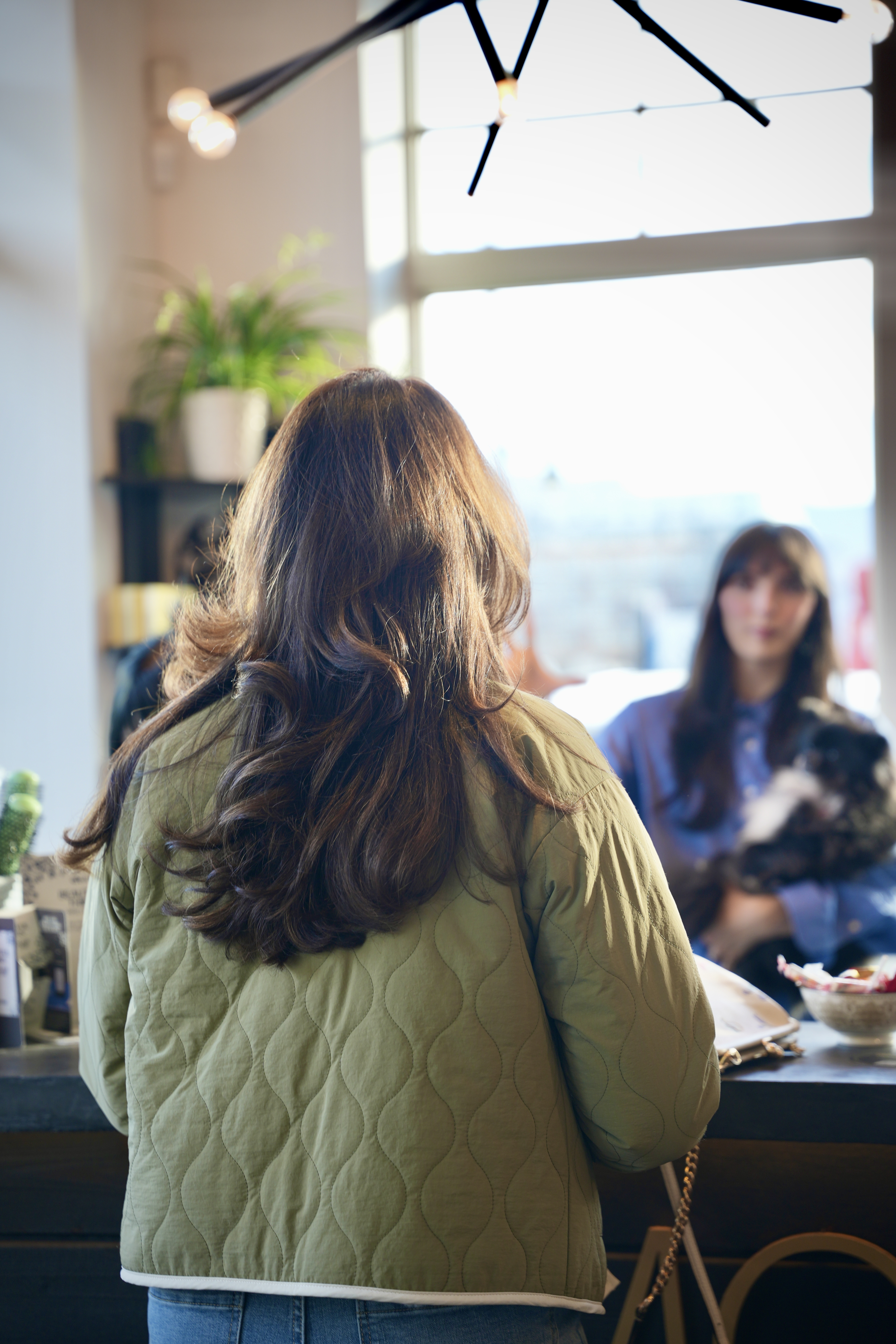 A guest greeted at the reception desk by a stylist holding the salon dog
