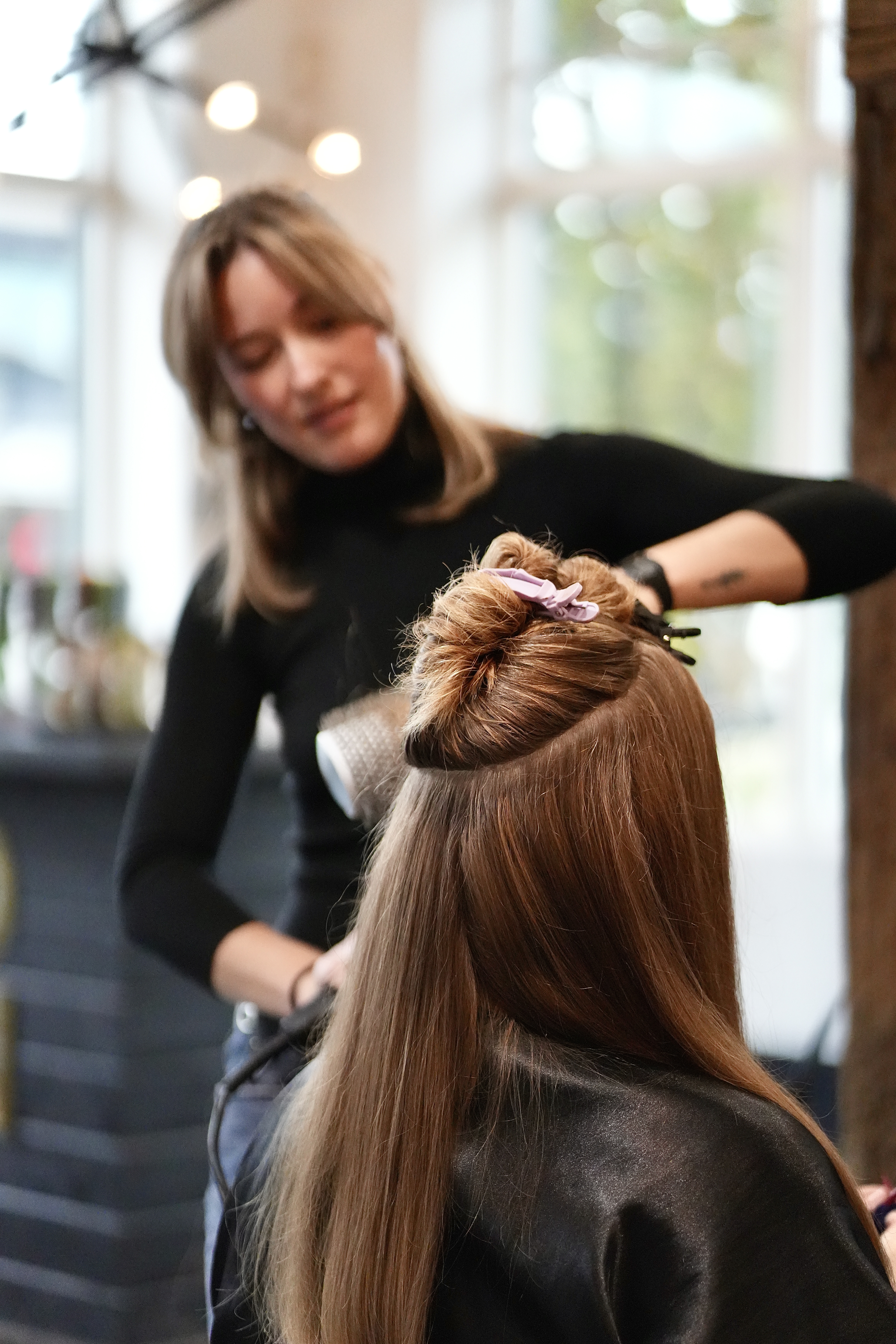 A stylist working on a guest's hair, hands engaged in the styling