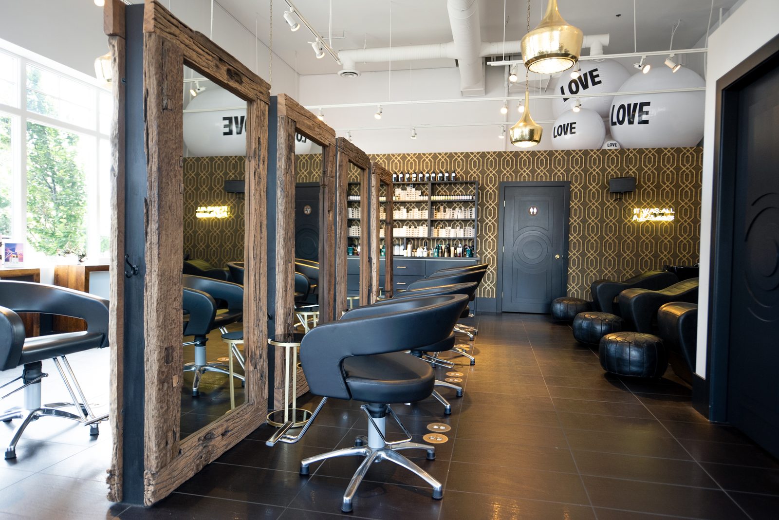 A wide view down the Mod Salon styling floor with warm light and the gold pendant lights overhead
