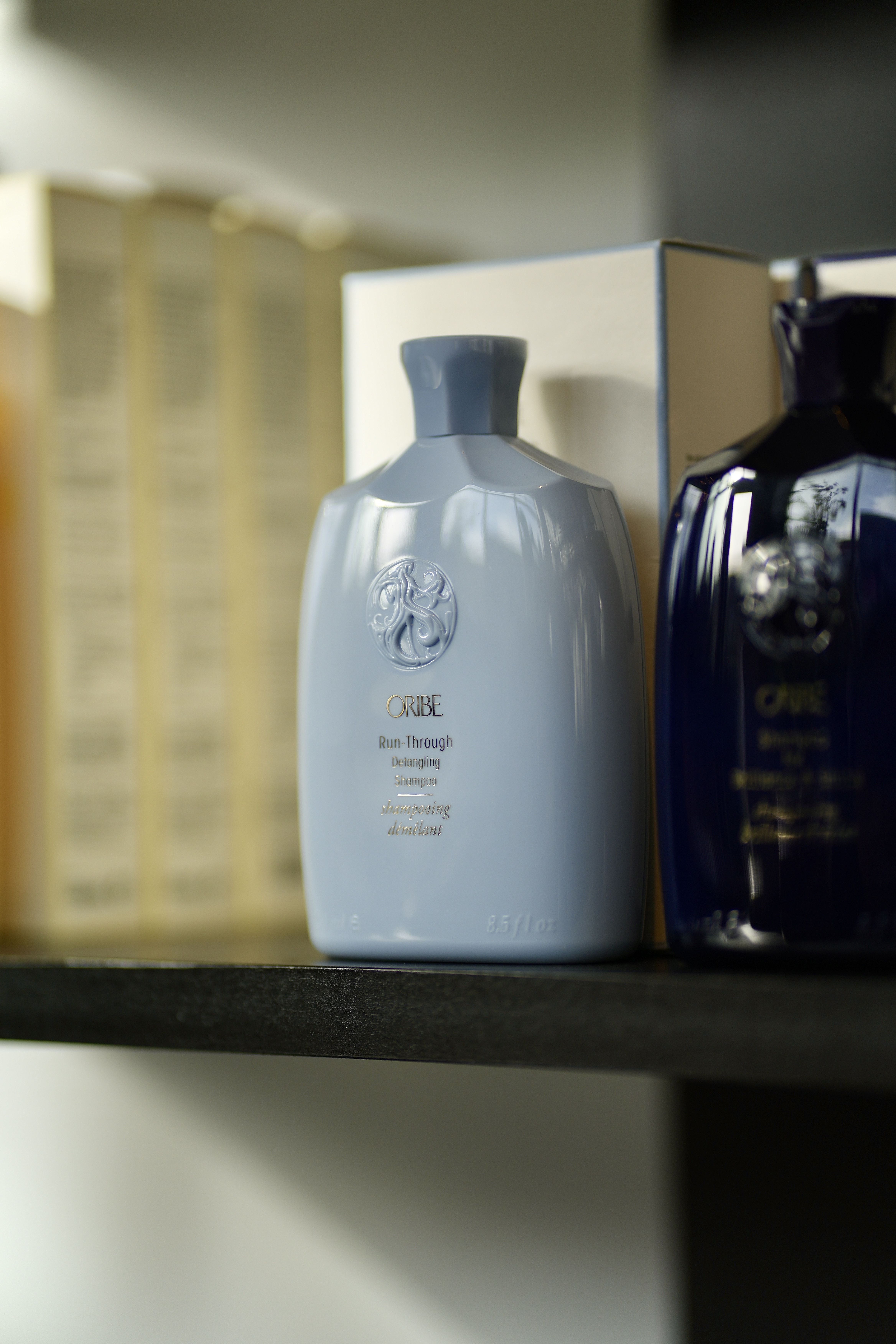 An Oribe shampoo bottle on the MOD product shelf, lit by warm window light