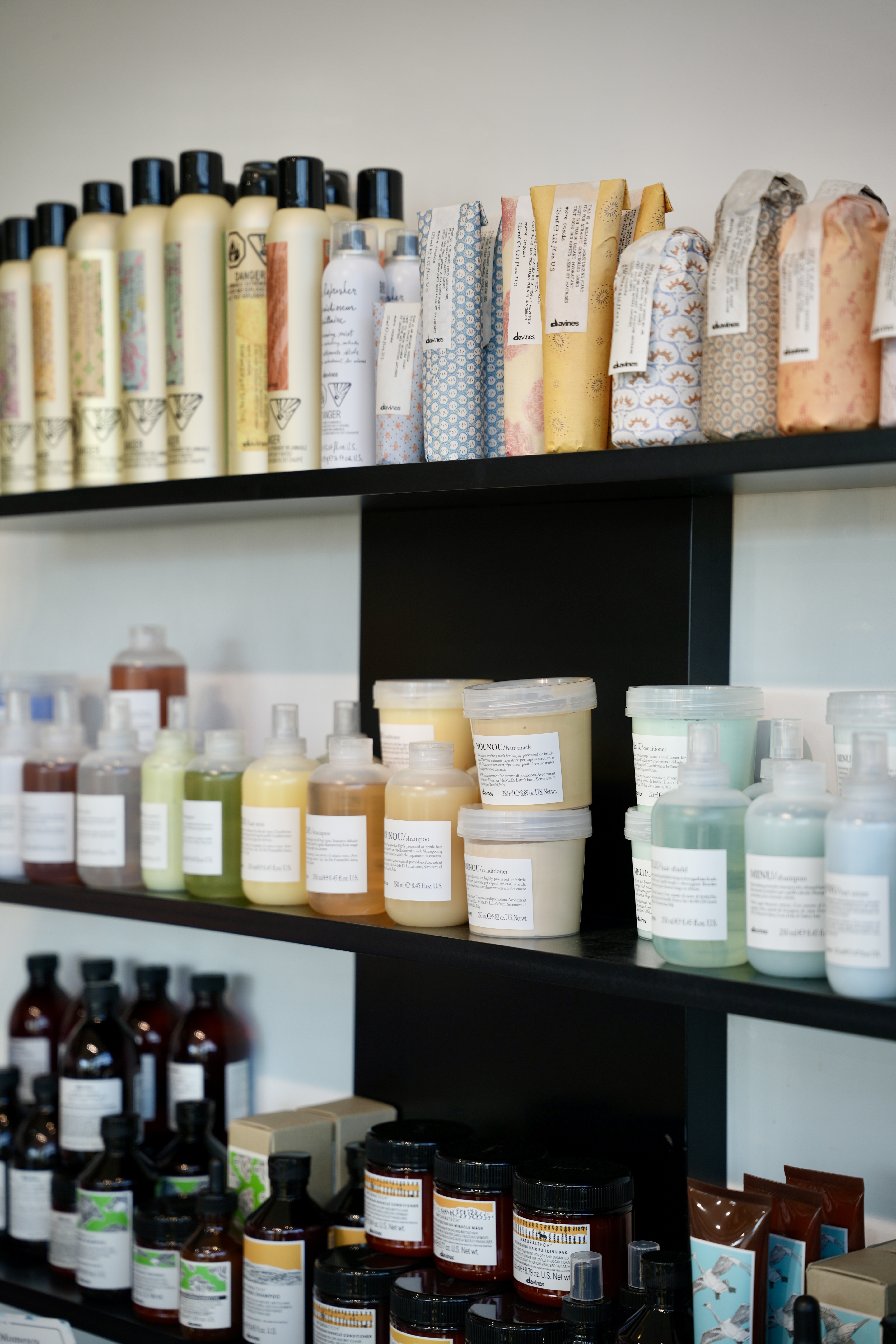 Detail of the product wall at Mod Salon, with carefully arranged shampoos, conditioners, and treatments on dark shelving