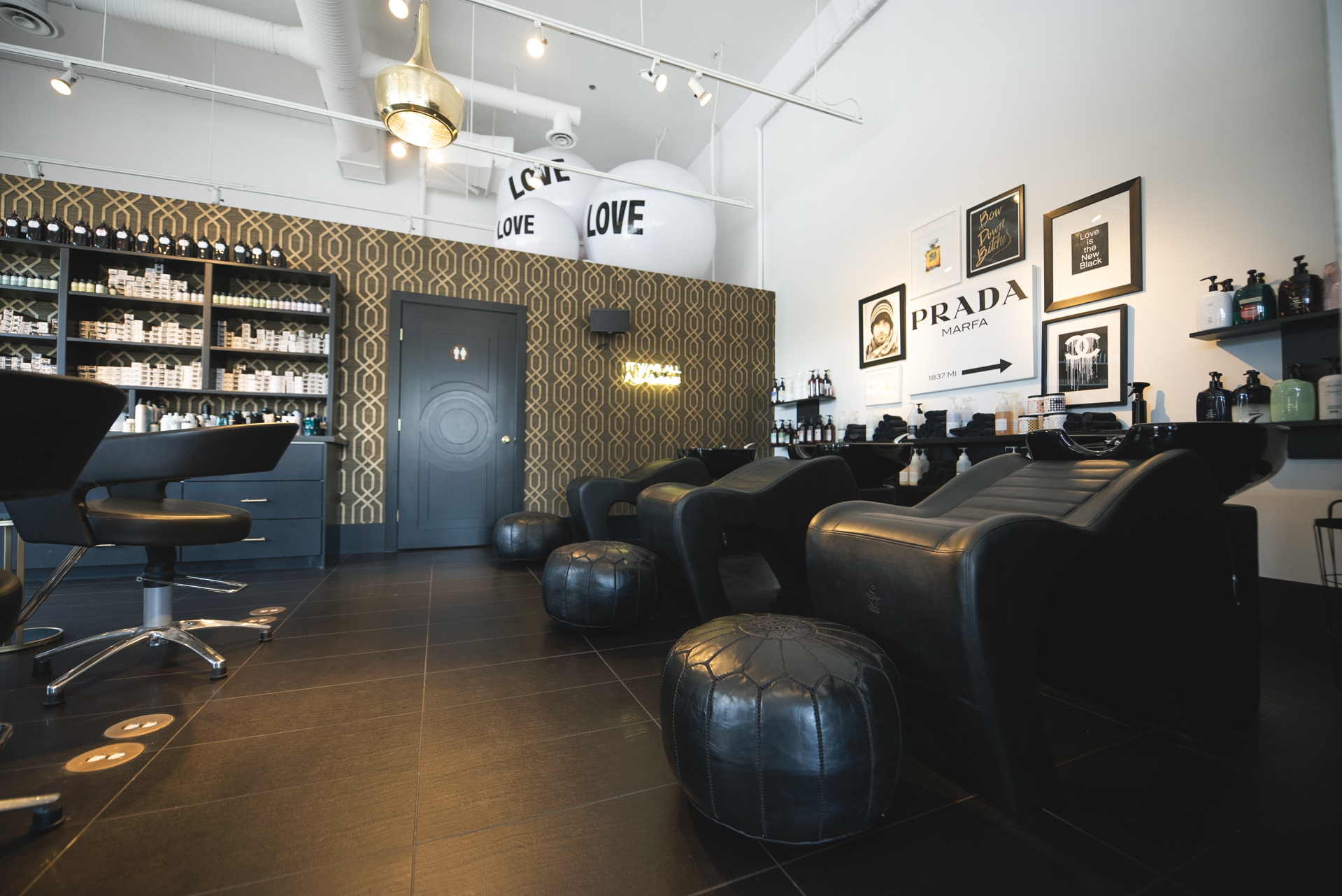 The wash basin area at MOD Salon with gold geometric wallpaper and leather chairs
